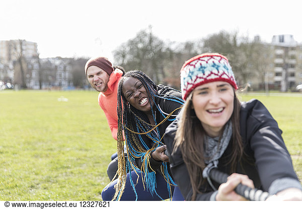 Determined team pulling rope in tug-of-war in park