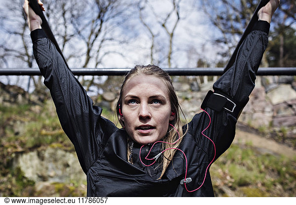 Determined woman exercising on monkey bars at outdoor gym