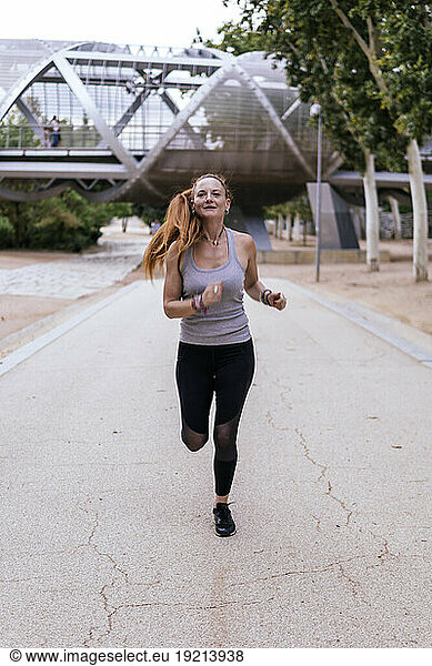 Determined woman jogging on footpath at park