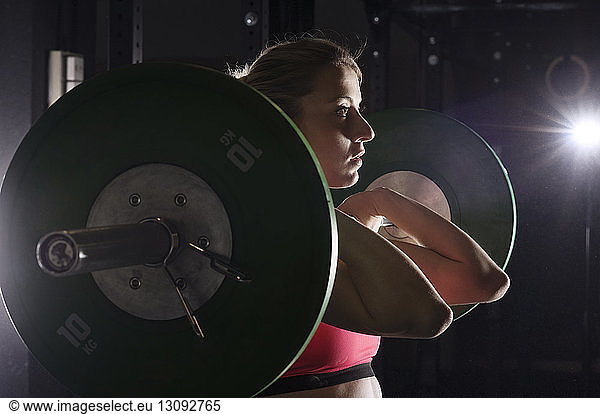 Determined woman lifting barbell in health club