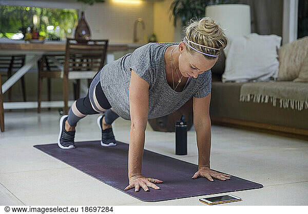 Determined woman practicing Plank Position on exercise mat at home