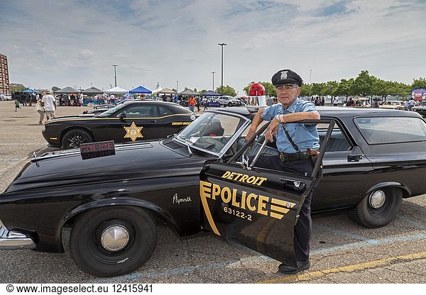 Detroit  Michigan - A former Detroit police officer with his 1963 Plymouth police car at an antique and custom car show  sponsored by the Detroit Police Department. The officer is wearing a police uniform from that era.