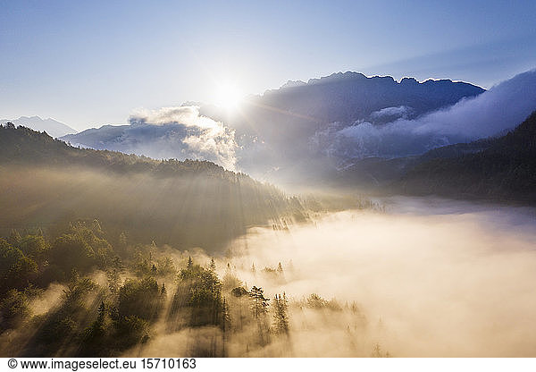 Deutschland  Bayern  Mittenwald  Die aufgehende Sonne beleuchtet den Nebel  der den Ferchensee und den umliegenden Wald bedeckt