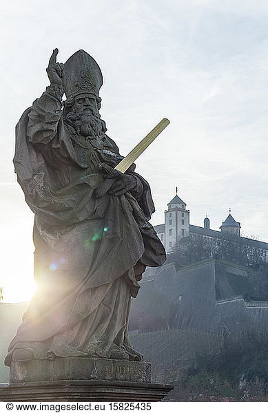 Deutschland  Bayern  Würzburg  Würzburg  Statue des Heiligen Kilian bei Sonnenuntergang mit der Festung Marienberg im Hintergrund