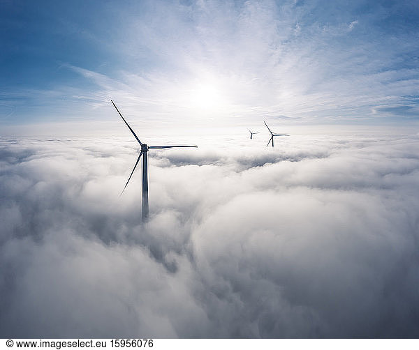 Deutschland  Luftaufnahme von in Wolken gehüllten Windturbinen bei Sonnenaufgang