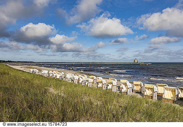 Deutschland  Mecklenburg-Vorpommern  Reihen von Strandkorbstühlen am sandigen Küstenstrand im Sommer mit Pier im Hintergrund