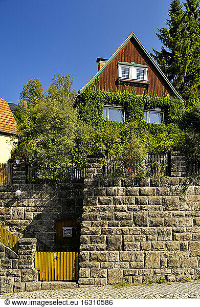 Deutschland  Sachsen  Hohnstein  Überwuchertes Haus hinter Steinmauer