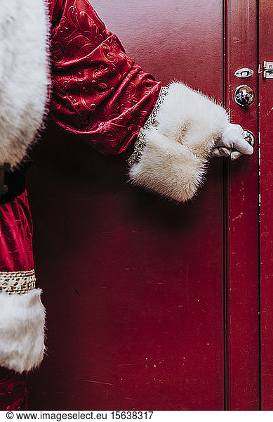 Die Hände des Weihnachtsmanns mit Handschuhen öffnen die Tür schließen sie