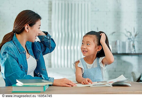 Die junge Frau  die ihre Tochter bei den Hausaufgaben betreut