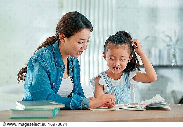 Die junge Frau  die ihre Tochter bei den Hausaufgaben betreut