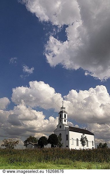 Die Kirche des niederländischen Dorfes Simonshaven unter einem dramatischen Himmel mit schweren Wolken.