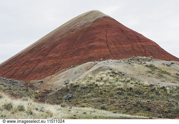 Die Landschaft des John Day Fossil Beds National Monument  Oregon. Kräftig gefärbte Felsen  die Flanken aus Stein  gefaltet und rot gefärbt.