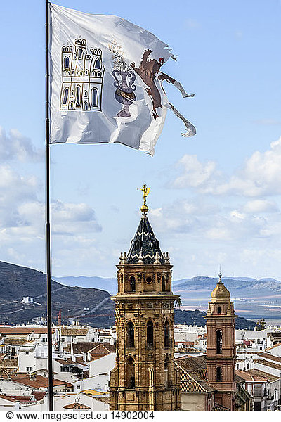 Die Stadt Antequera mit Kirchtürmen und einer zerrissenen  verwitterten Flagge im Vordergrund; Antequera  Malaga  Spanien