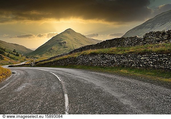 Die Straße Kirkstone Pass A592 schlängelt sich in der Abenddämmerung durch die atemberaubende Landschaft des Lake District National Park  Cumbria  England. Die Straße ist lokal als The Struggle bekannt und der Nationalpark gehört zum UNESCO-Weltkulturerbe.
