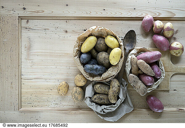 Different varieties of raw potatoes on rustic wooden background