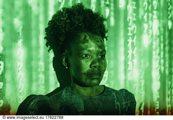 Digital code falling on woman with Afro hairstyle in front of wall