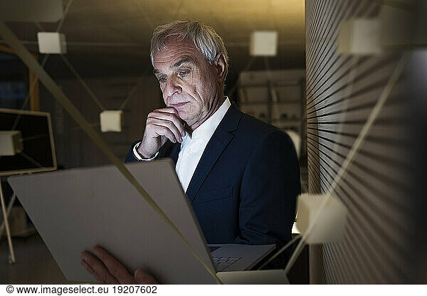 Digital composite image of thoughtful businessman with laptop in office