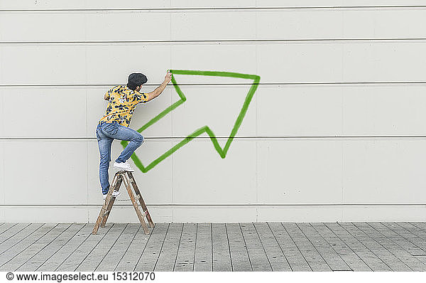 Digitale Komposition eines jungen Mannes  der einen Pfeil an eine Wand zeichnet