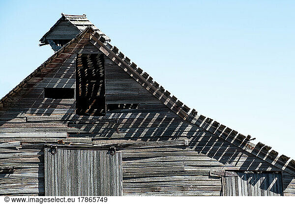 Dilapidated boards cast long shadows on a long forgotten barn in