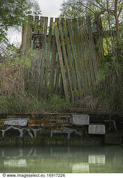 Dilapidated wooden fence on canal watefront.