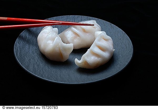Dim Sum  filled dumplings on black plate with red chopsticks  Germany  Europe
