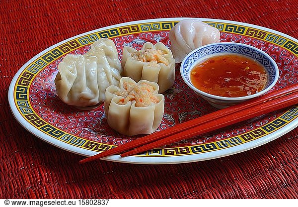 Dim Sum  filled dumplings on plate with red chopsticks and chilli sauce  Germany  Europe