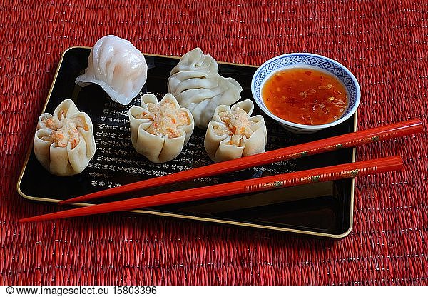 Dim Sum  filled dumplings on tray with red chopsticks and chilli sauce  Germany  Europe