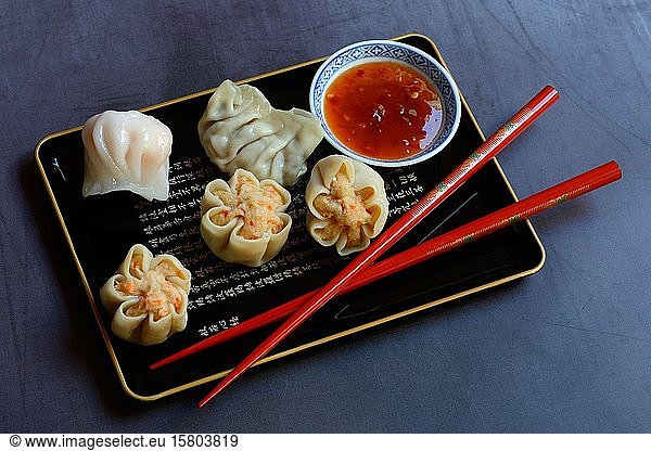 Dim Sum  filled dumplings on tray with red chopsticks and chilli sauce  Germany  Europe
