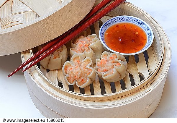 Dim Sum  filled dumplings with chopsticks and chilli sauce in steam baskets  Germany  Europe