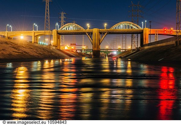 Diminishing perspective of Los Angeles river and 6th street bridge illuminated at night  Los Angeles  California  USA