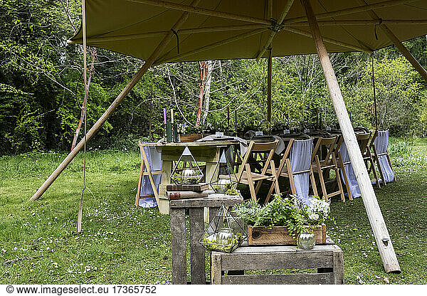 Dining table and chairs under a canopy for a woodland naming ceremony.