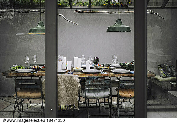 Dining table with place setting in backyard greenhouse