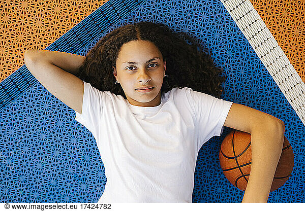 Directly above portrait of girl with basketball lying on court