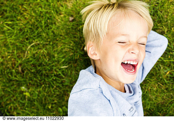 Directly above shot of boy laughing while lying on grass