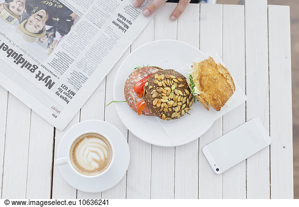 Directly above shot of breakfast with smart phone and newspaper on cafe table