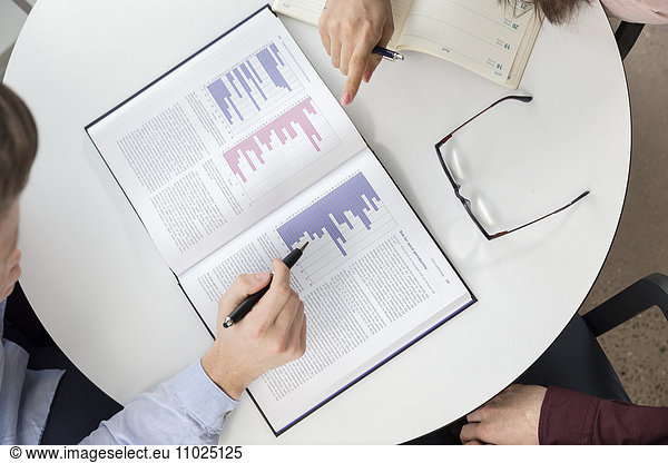 Directly above shot of business people analyzing graphs in meeting