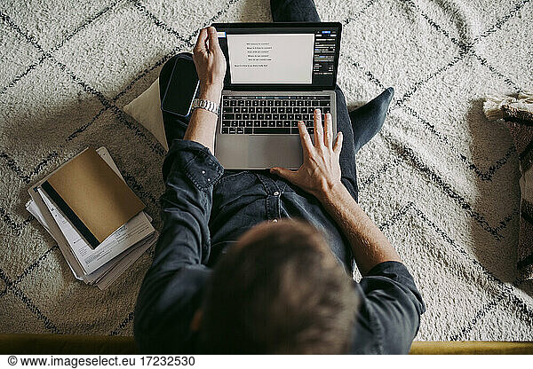 Directly above shot of businessman working on laptop at home
