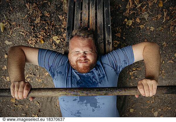 Directly above shot of determined obese man doing bench press at park