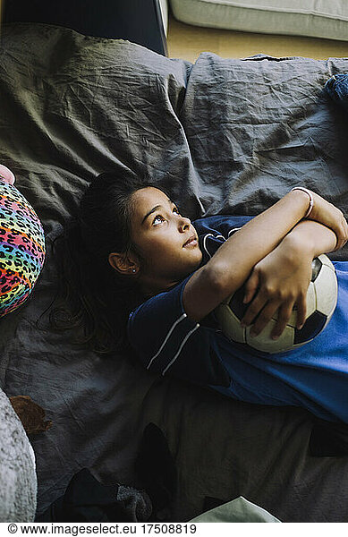 Directly above shot of girl contemplating while lying down in bedroom