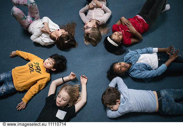 Directly above shot of school children lying on floor in classroom