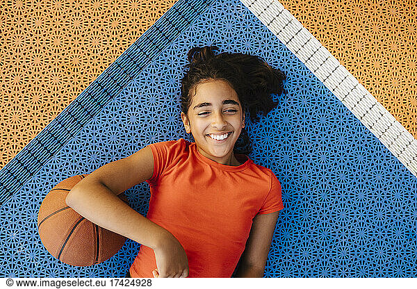 Directly above shot of smiling girl lying down on court