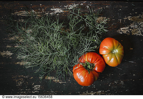 Directly above shot of tomatoes with dill on wooden table
