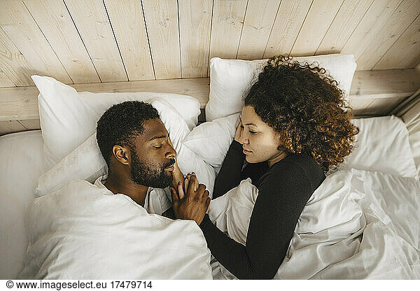 Directly above view of couple sleeping on bed in hotel