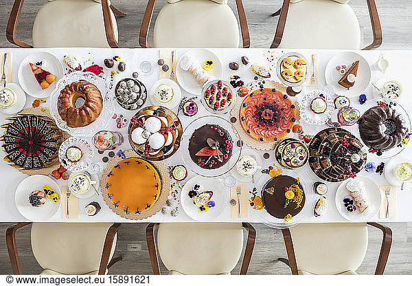 Directly above view of dining table filled with all kinds of snacks and desserts