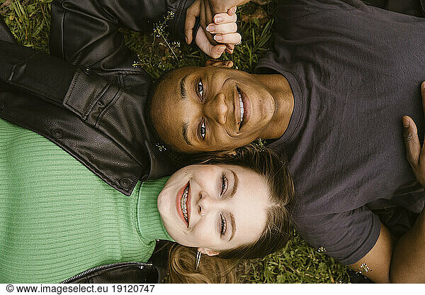 Directly above view of happy young woman and man lying on grass