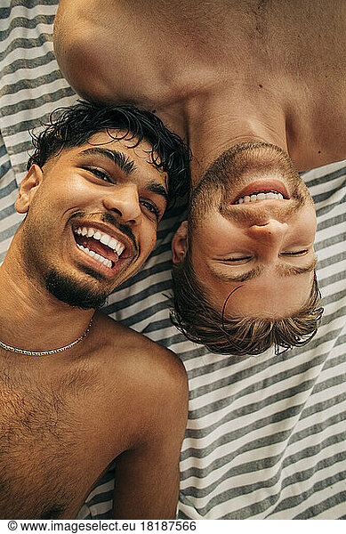 Directly above view of shirtless male friends lying down together
