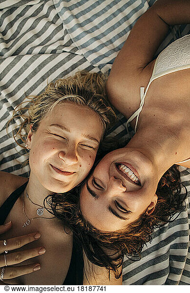Directly above view of woman with eyes closed lying down by smiling female friend