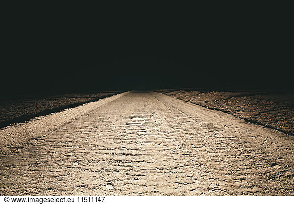 Dirt road in desert illuminated by car headlights  Death Valley National Park  USA