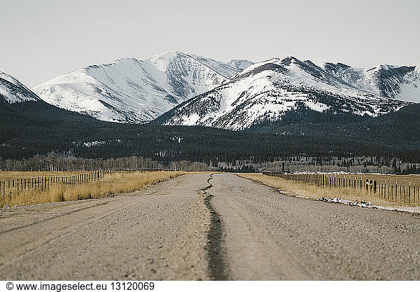 Dirt road leading towards snowcapped mountains