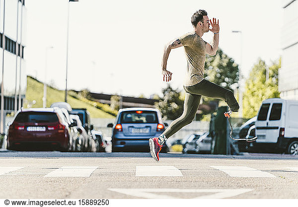 Disabled athlete with leg prosthesis exercising in the city on a zebra crossing